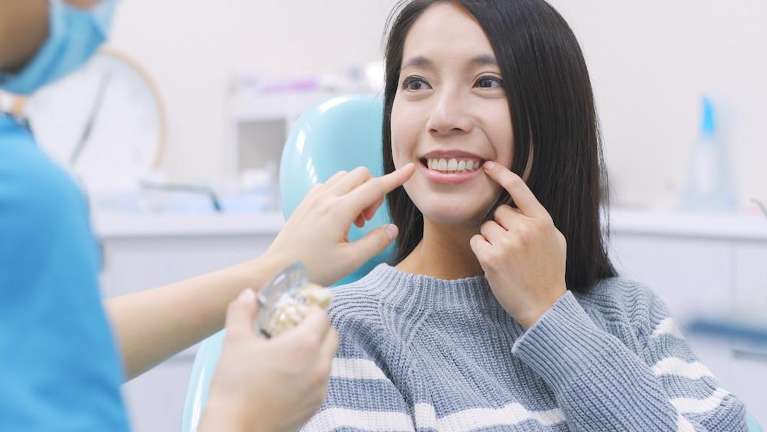 woman sitting in exam chair smiling | dental extractions narre warren